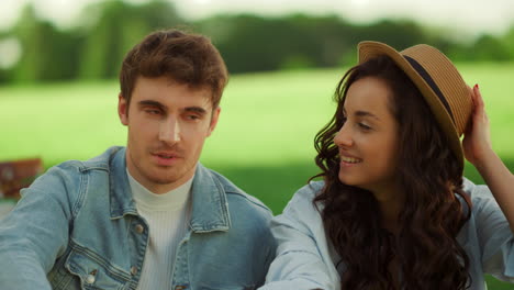 smiling girl and guy speaking on lawn in park. couple laughing on picnic