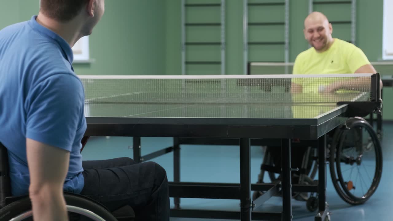 체어에 앉아 있는 남자가 핑핑을 하고, 장애인들이 탁구를 하고, 장애인의 재활, 패럴림픽 스포츠.