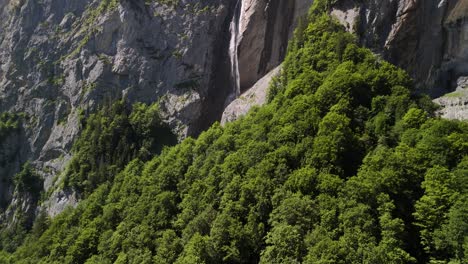 forest at waterfall base, rocky cliff swiss alps mountains, switzerland