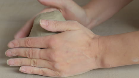 pottery artist preparing clay with her hands for working on the throwing wheel