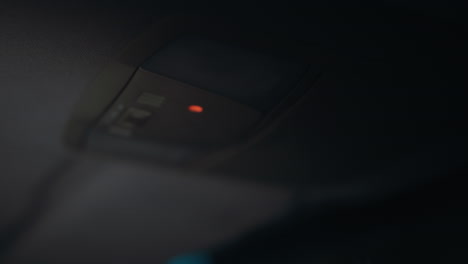 first-person view of a woman turning on the car light at night. her hand with black painted nails is clearly visible as she reaches for the light switch inside the car