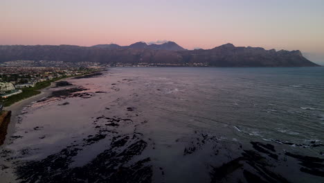 Shallow-coastal-reefs-and-Strand-beachfront-properties,-twilight-drone-pan