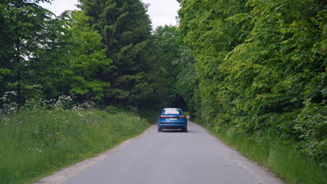 electric suv car driving among green nature. new audi e-tron blue color with highlights on. sportive car model moving on a road in the forest. save environment.