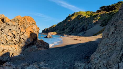 hidden cove with sandy beach, sand dunes and rugged rocky cliffs in outdoor nature of wellington, new zealand aotearoa