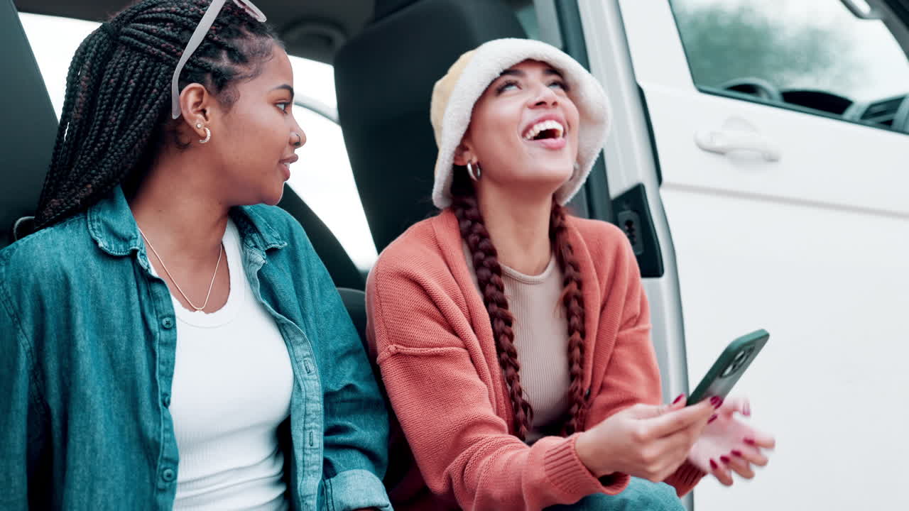 Two friends laughing in a van during a road trip