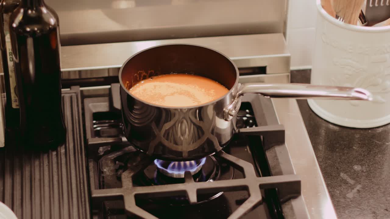 creamy tomato soup simmering on a gas stove. handheld shot.