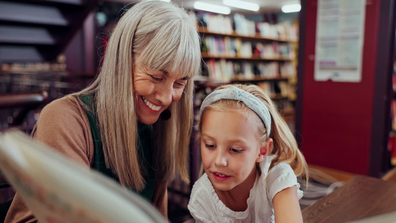 Oma leest met kleindochter in de bibliotheek