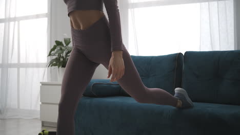 sporty slim woman is training in room athletic lady is doing exercises for legs muscles closeup of bottom body part female sporty person