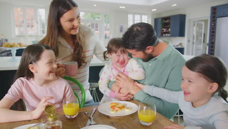 family with down syndrome daughter sitting around table at home eating breakfast