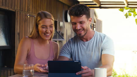 Lächelndes-Paar,-Das-Draußen-Zu-Hause-Ein-Digitales-Tablet-Nutzt,-Urlaub-Bucht-Oder-Online-Einkauft