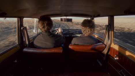 couple traveling in retro car through open rural landscape