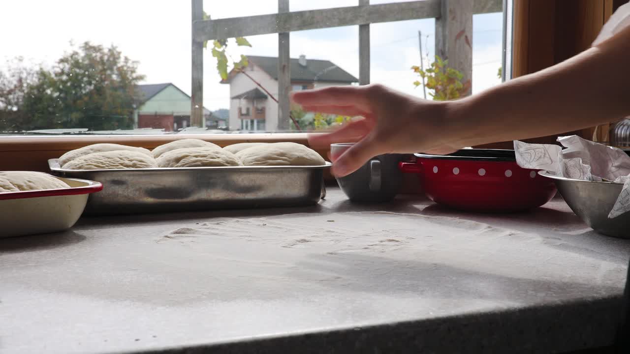 Closeup shot of hands of young woman applying flour on dough, kneading dough, making bread using traditional recipe, isolated on black background 4k footage