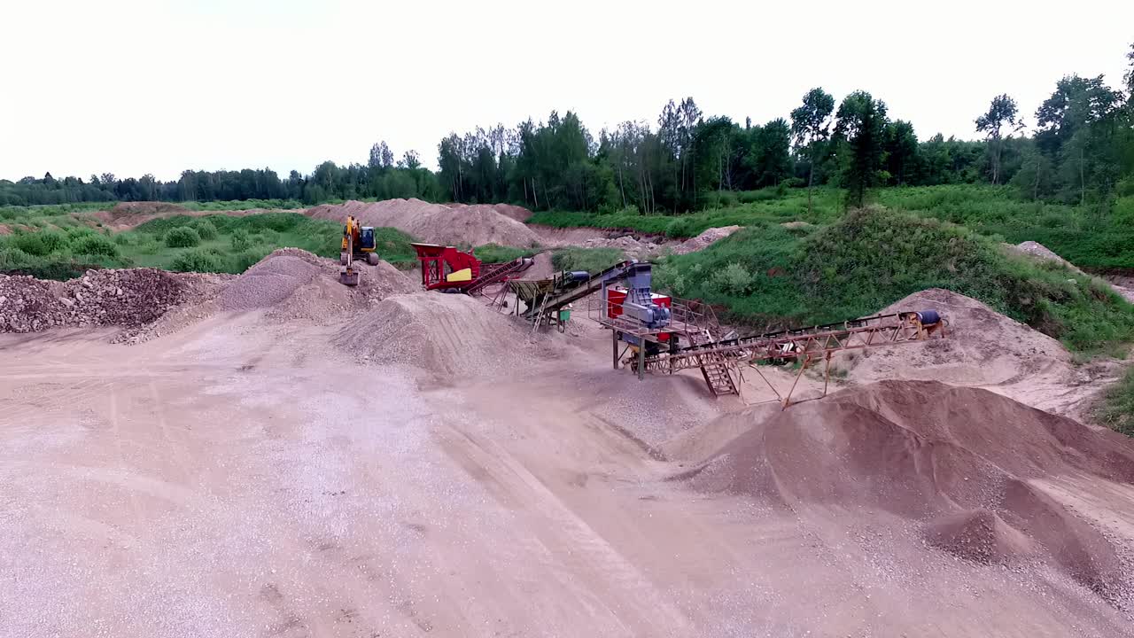 Drone view of a sand quarry, machinery working on piles