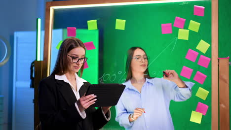 collaboration in a creative workspace. two women collaborate in a modern office using a digital tablet and sticky notes for brainstorming ideas