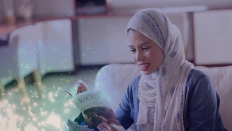 animation of leaves over biracial woman in hijab smiling and reading book