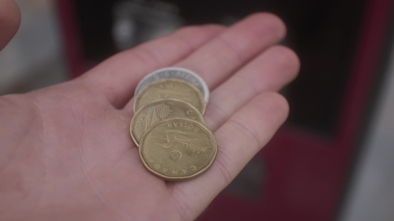monedas de uno y dos dólares canadienses en la palma de la mano
