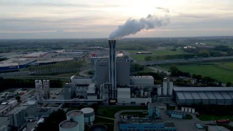 Aerial-of-smoking-factory-chimney-with-a-setting-sun-in-the-background