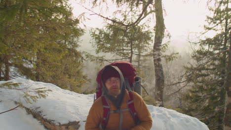tourist climbing mountain trail with trekking poles in winter