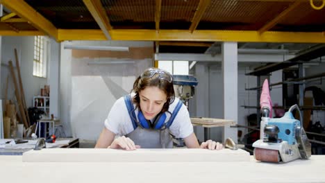 female welder examining a wooden plank 4k