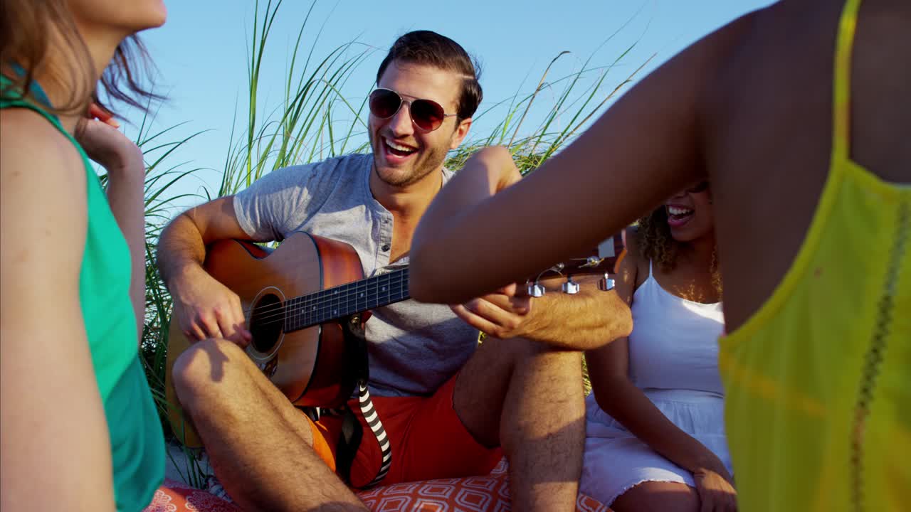 jóvenes amigos multiétnicos disfrutando de un picnic en la playa