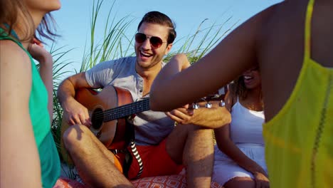 jóvenes amigos multiétnicos disfrutando de un picnic en la playa