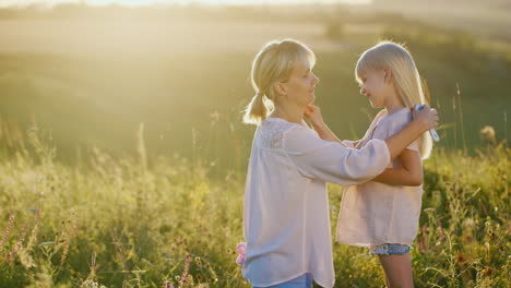 Una-Joven-Madre-Con-Cabello-Rubio-Peinando-A-Su-Hija-Al-Aire-Libre