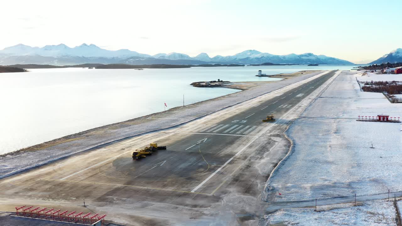 여러 대의 쟁기 트럭이 노르웨이 årø 몰데 공항의 활주로에서 눈을 제거합니다.