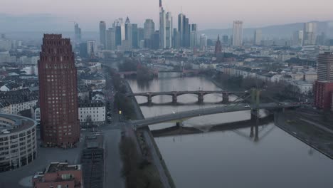 reveiling the frankfurt skyline with hotel tower and river main in the foreground at dusk on a misty winter morning