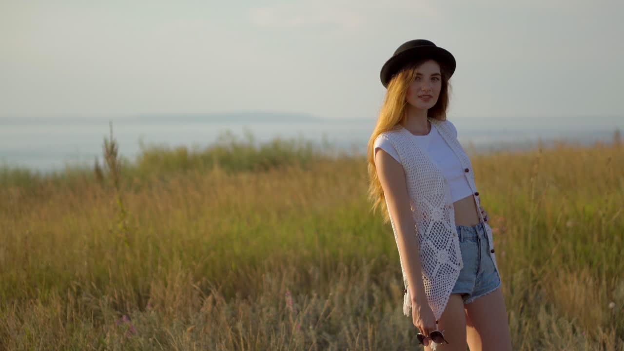mujer en estilo boho disfrutando de la puesta de sol en un campo