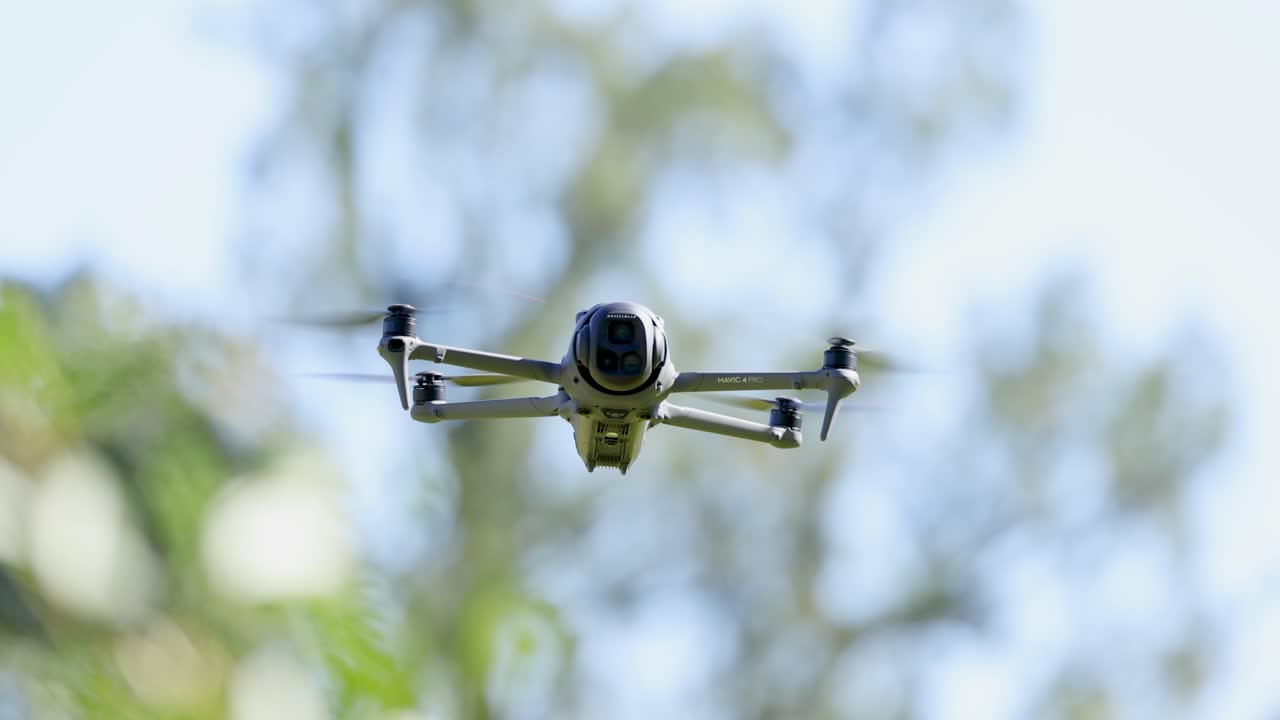A drone hovers steadily in a sunlit, leafy environment on the Gold Coast, showcasing smooth aerial motion and natural surroundings