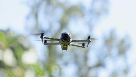 a drone hovers steadily in a sunlit, leafy environment on the gold coast, showcasing smooth aerial motion and natural surroundings