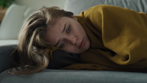 caucasian sad woman sitting on the sofa and covering the blanket at home.