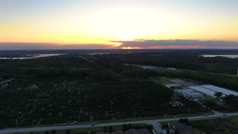 Flying-over-lakeside-neighborhood-and-orange-tree-farm-during-a-beautiful-Florida-sunset