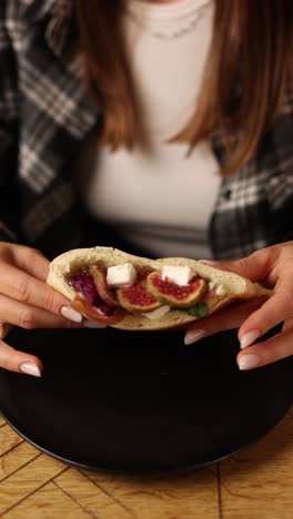 woman eating a fig and goat cheese pita sandwich