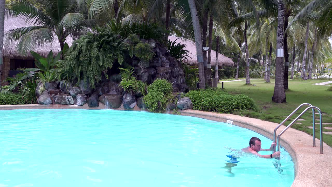 un hombre emerge de las escaleras de la piscina al aire libre
