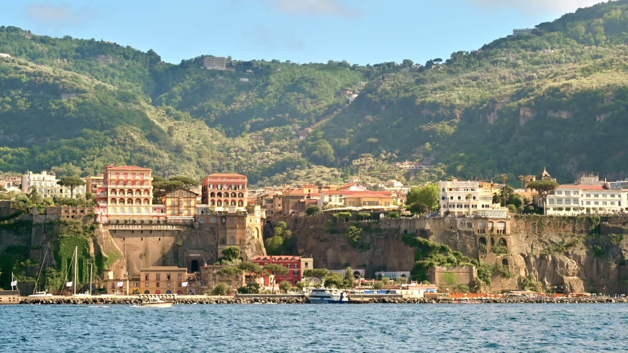 Vista della costa del Mar Tirreno a Sorrento, Italia. File di edifici, spiaggia, scogliere, yacht in movimento, vegetazione. Vista da una barca