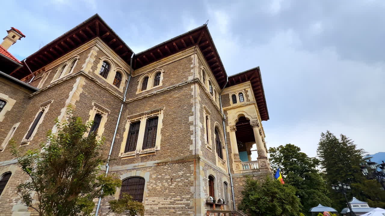 Busteni, Romania, 17 July 2025: Beautiful facades of Cantacuzino Castle, Busteni, Romania. Two priests walk along the historical building