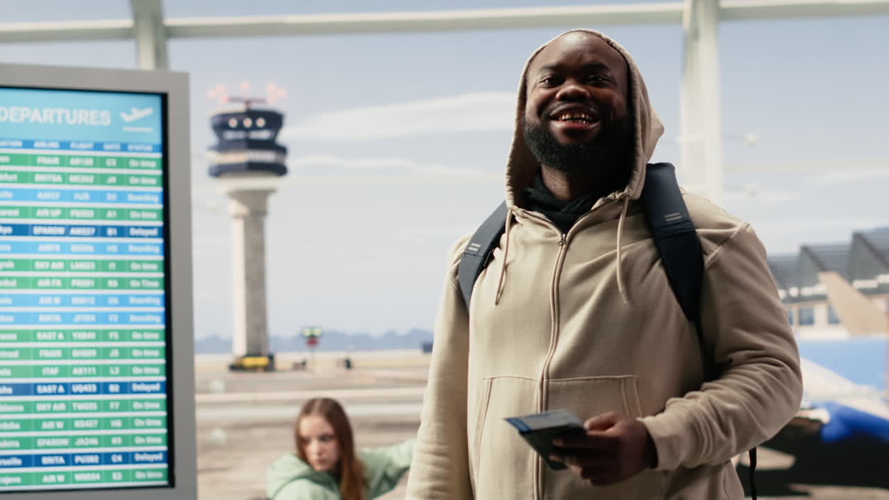 Viaggiatore felice che tiene passaporto e biglietto al terminal dell'aeroporto.