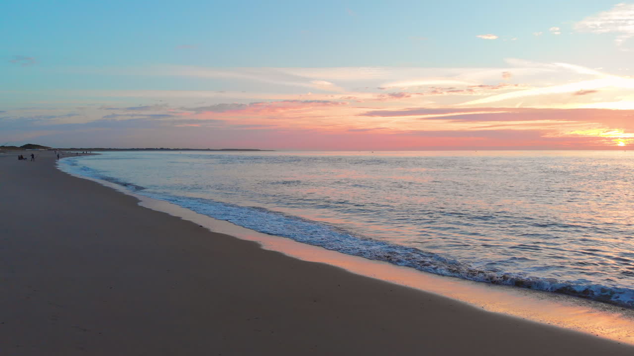 una marea baja tranquila en la playa cerca de la barrera de marejada en el suroeste de los países bajos, durante la puesta de sol