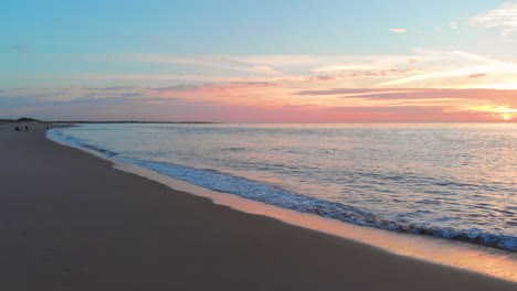 Una-Marea-Baja-Tranquila-En-La-Playa-Cerca-De-La-Barrera-De-Marejada-En-El-Suroeste-De-Los-Países-Bajos,-Durante-La-Puesta-De-Sol