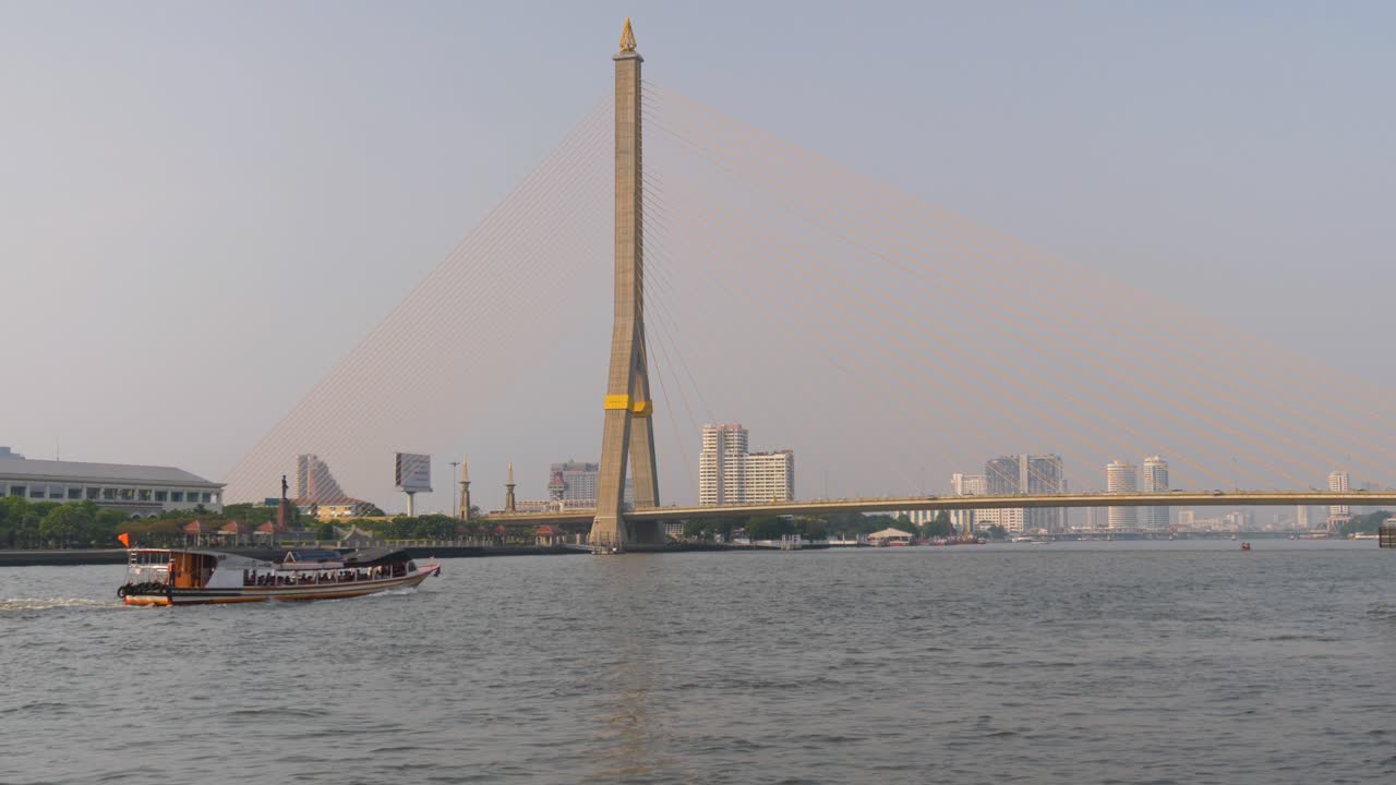 A boat crossing the Chao Phraya River under the Rama VIII Bridge in Bangkok, Thailand