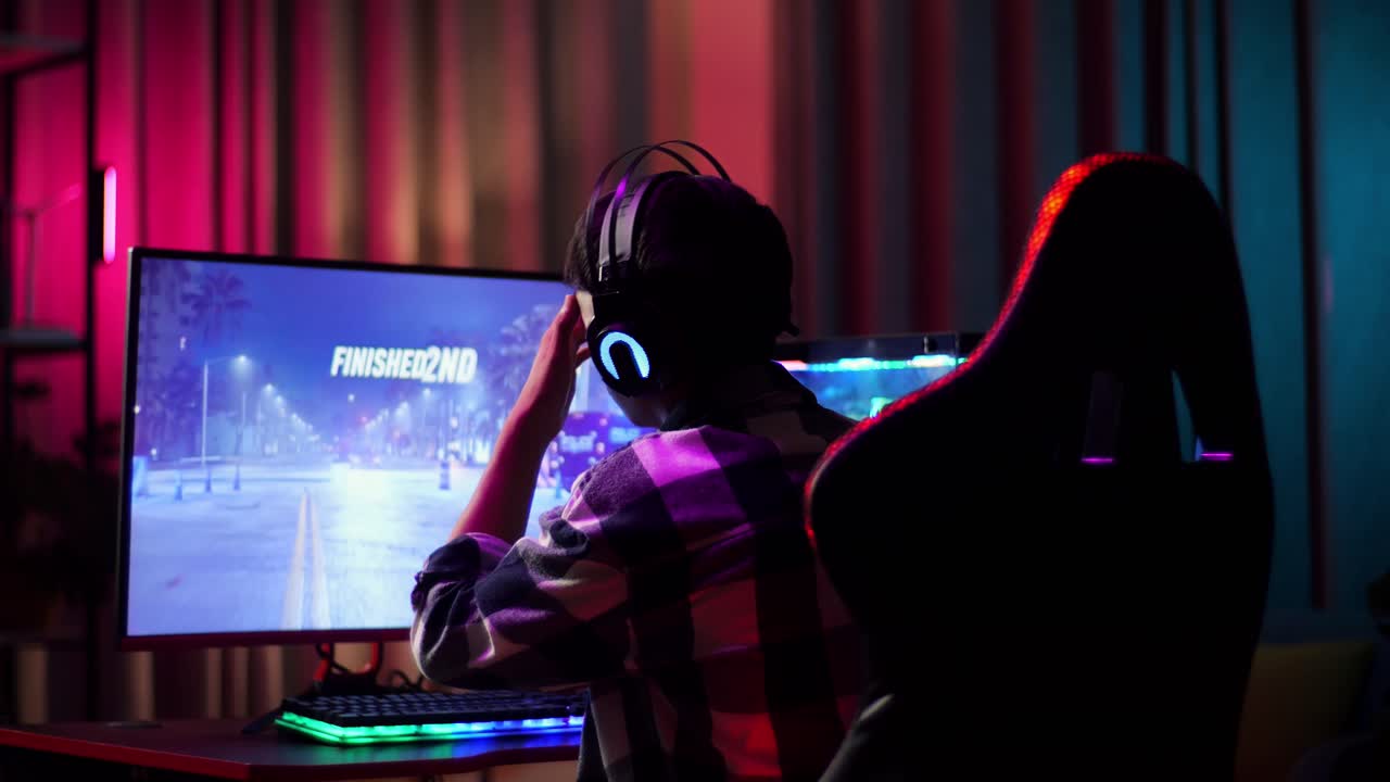Ragazzo adolescente asiatico videogiocatore che perde mentre gioca a un videogioco di corse al computer
