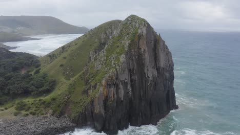 drone flying towards rocky cliff and green grass rolling hills transkei, south africa