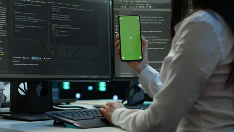 Worker-overseeing-data-center-using-green-screen-mobile-phone