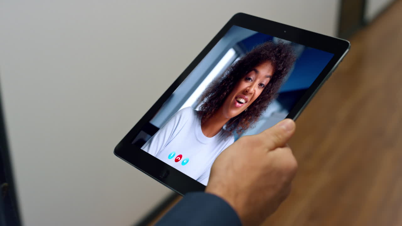 Donna sorridente che si gode una videochat tramite tablet con un uomo d'affari sconosciuto che cammina in ufficio