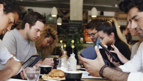 friends using digital devices at lunch meeting