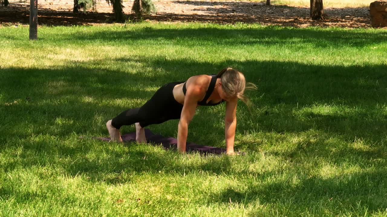 A fit healthy and muscular woman does pushups and yoga in a public park