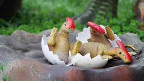 three baby dinosaurs hatching from eggshells in a park exhibit