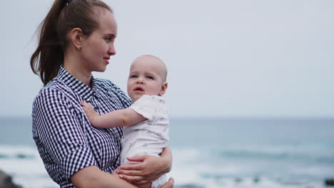 en el horizonte del mar y la playa, un conmovedor retrato congela un momento de un beso de una madre compartido con su hija. una familia encantada de vacaciones, con la madre envolviendo a su bebé en un abrazo