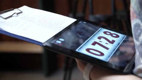 person holding a tablet with a timer and notes